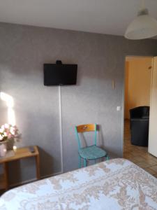 a room with a bed and a chair and a television at la chaume in Laugère