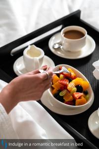 a woman eating a bowl of fruit with a cup of coffee at Grand Cosmopolitan Hotel in Dubai