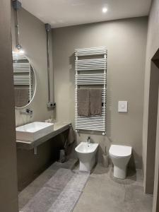 een badkamer met een wastafel, een toilet en een spiegel bij TRETRE in Bologna