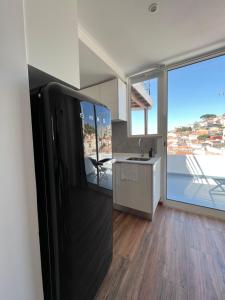 een keuken met een zwarte koelkast en een wastafel bij Castello Prime Suites in Lissabon