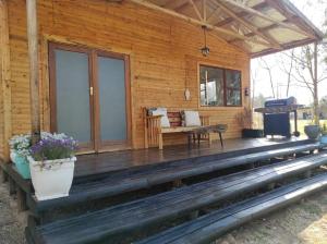 porche de una cabaña de madera con banco y parrilla en River Cabin, en Roodepoort