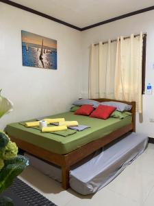 a bedroom with a bed with green sheets and red pillows at Alona Bohol Backpackers Hostel in Panglao