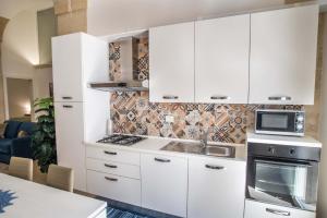 uma cozinha com armários brancos e um forno com placa de fogão em La Volta - Casa Vacanze em Galatina