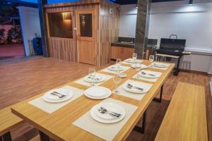 a long wooden table with plates and wine glasses at Grand Gala Villa in Pattaya South