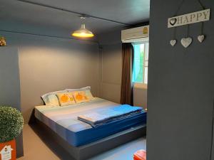 Un pequeño dormitorio con una cama con un cartel feliz en la pared en Love CNX Guesthouse en Chiang Mai