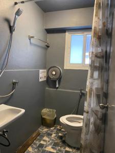 a bathroom with a toilet and a sink and a window at Love CNX Guesthouse in Chiang Mai