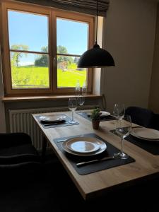 een tafel met borden en wijnglazen en een raam bij Mein Traumblick in Rettenberg