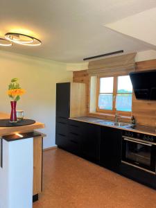 eine Küche mit schwarzen Schränken, einem Waschbecken und einem Fenster in der Unterkunft Mein Traumblick in Rettenberg