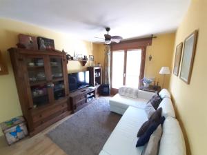 sala de estar con sofá blanco y TV en Apartamento en Pirineos, en Bielsa