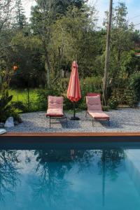 duas cadeiras e um guarda-sol junto a uma piscina em Maison Balaguera em Saint-Jean-de-Marsacq