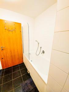 a bathroom with a bath tub and a wooden door at Modern Mountain Apart 2 - directly by Skiing area in Rauris