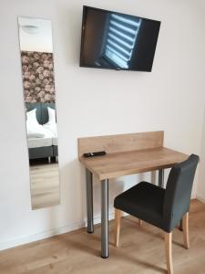 a desk with a chair and a television on a wall at Ferienwohnung Ewa in Ellenz-Poltersdorf