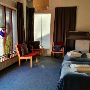 a hotel room with two beds and two chairs at The Bank Sleeping in Neskaupstaður