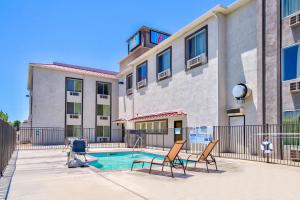 un edificio de apartamentos con piscina y 2 sillas en Motel 6-Hesperia, CA - West Main Street I-15, en Hesperia