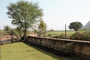un mur de retenue avec un champ et des arbres en arrière-plan dans l'établissement Shivir Aranya - Wilderness Resort, à Alwar