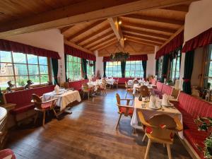 a restaurant with tables and chairs and windows at Hotel Piedibosco in Moena