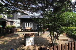 a house with a fence and a tree in the yard at Hunston Mill Self Catering Dog Friendly in Chichester