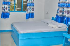 a blue bed in a room with windows at Beach House Paje in Paje