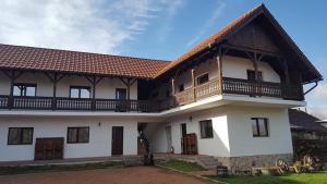 a large white house with a wooden roof at Pensiunea Alex in Marga