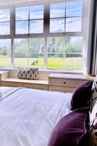 a bedroom with a bed and a large window at STUNNING LODGE MINUTES FROM THE SEA AND GOLF COURSE in Longniddry