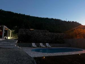 a swimming pool with two chairs and a stone wall at Vila Nomada in Blagaj