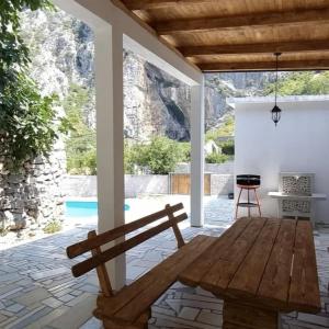 a patio with a wooden bench and a grill at Vila Nomada in Blagaj