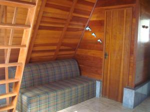 Habitación con sofá en una habitación con paredes de madera. en Chalès em Ilhabela Litoral Norte en Ilhabela