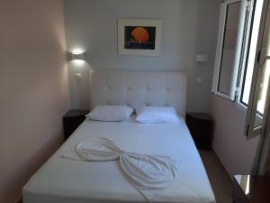 a white bed in a room with a window at Pleasant apartment in Mpenitses with terrace in Benitses +32 photos