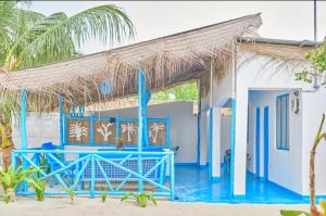 ein blaues Gebäude mit einem Strohdach am Strand in der Unterkunft Beach House Paje in Paje