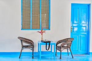 zwei Stühle und ein blauer Tisch mit Pflanze drauf. in der Unterkunft Beach House Paje in Paje