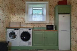 a kitchen with a washing machine and a window at Suir Valley Cottage. 