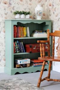 a book shelf filled with books next to a chair at Suir Valley Cottage. 