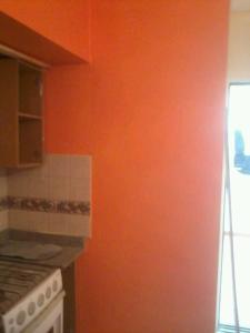 uma cozinha com paredes cor de laranja e um fogão em Residencia "Libertad" em San Andrés