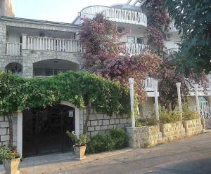 a building with a gate and flowers on it at Apartmani Mustur in Bijela