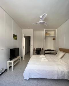 Schlafzimmer mit einem weißen Bett und einem Deckenventilator in der Unterkunft Spacious 4 Bedrooms apartment for family or several friends in San Bartolomé de Tirajana