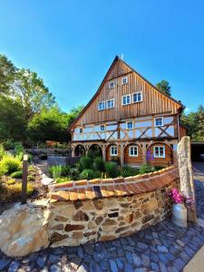 uma grande casa de madeira com um banco de pedra em frente em Pferdehof am Burgsberg, Ferienzimmer, Monteurzimmer em Seifhennersdorf