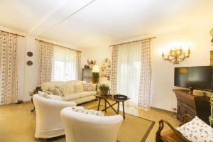 sala de estar con muebles blancos y TV de pantalla plana en Villa Monserrato - Goelba, en Porto Azzurro
