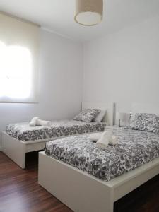 two beds in a room with white walls and wood floors at Gran piso en zona comercial Malaga in Málaga