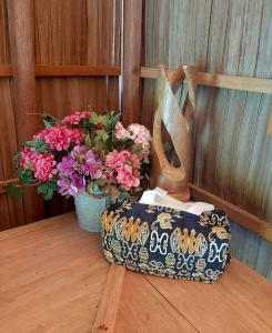 a table with a vase of flowers and a purse at Frances Homestay - Raja Ampat in Pulau Mansuar
