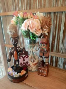 two wooden figurines on a shelf with a vase of flowers at Frances Homestay - Raja Ampat in Pulau Mansuar