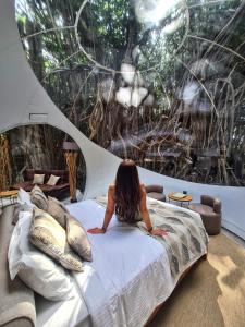 a woman laying on a bed in front of a window at Bubble Lodge Ile aux Cerfs Island in Ile aux Cerfs