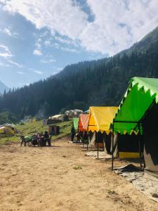 eine Gruppe von Zelten auf einem Feld mit Bäumen im Hintergrund in der Unterkunft City Escape Camps and Cafe Kheerganga in Kheerganga