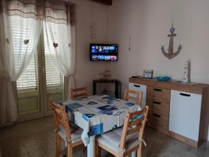 - une salle à manger avec une table, des chaises et une télévision dans l'établissement Casa del Pescatore, à Trappeto