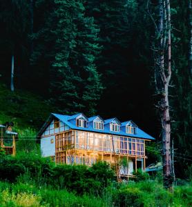 a large house with a blue roof in a forest at The Villster Resort in Kasol