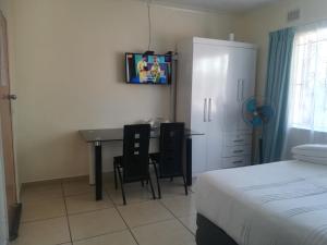 a bedroom with a desk and a bed and a table at 25 Jacaranda Lodge & Backpackers in Pinetown