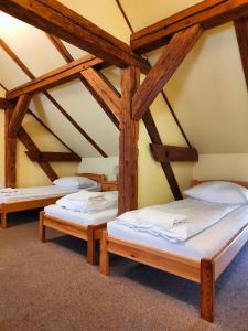 three beds in a room with wooden beams at Karczma u Wallenroda in Ryn
