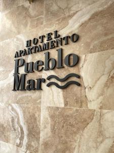 Hotel Apartamentos Pueblo Mar في كاليبي: علامة لمدخل الفندق إلى بويرتو أنتيغوا بويرتو مارينا