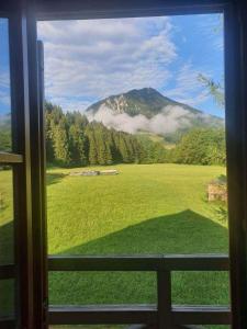 una ventana con vistas a un campo con una montaña en Villa Dona, en Kranjska Gora