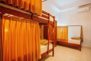 two bunk beds in a room with orange curtains at Kamasanti Hostel in Nusa Penida