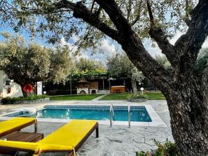 a swimming pool with a yellow bench and a tree at Olive Sense Villa with jacuzzi and sauna in Afantou